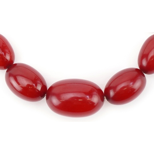 2304 - Cherry amber coloured graduated bead necklace, the largest bead approximately 25mm x 17mm in diamete... 