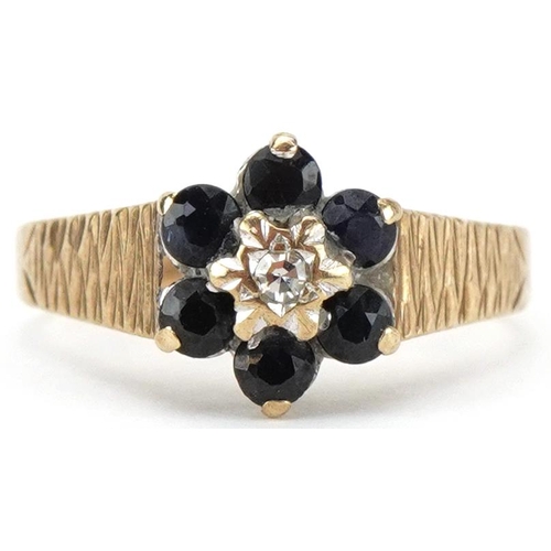 2389 - 9ct gold diamond and blue spinel flower head ring with engine turned shoulders, size I/J, 1.7g