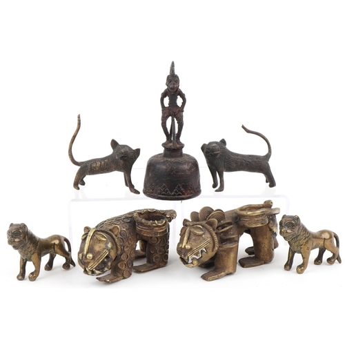 535 - Six African Benin bronzed mythical lions and a figural table bell, the largest 13.5cm high