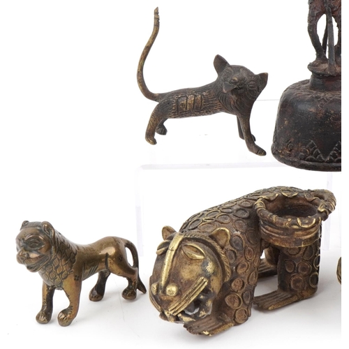 535 - Six African Benin bronzed mythical lions and a figural table bell, the largest 13.5cm high