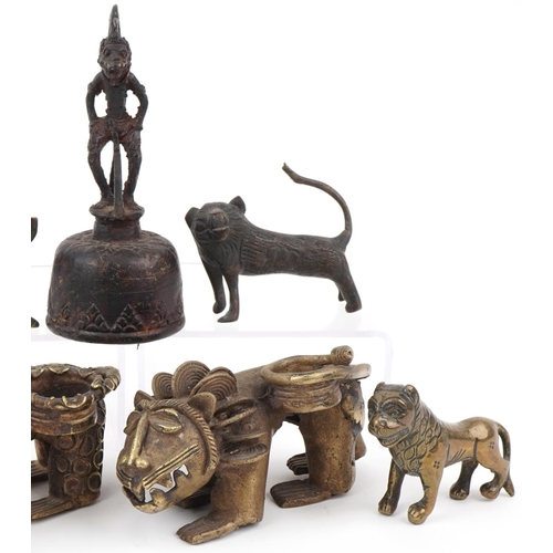 535 - Six African Benin bronzed mythical lions and a figural table bell, the largest 13.5cm high