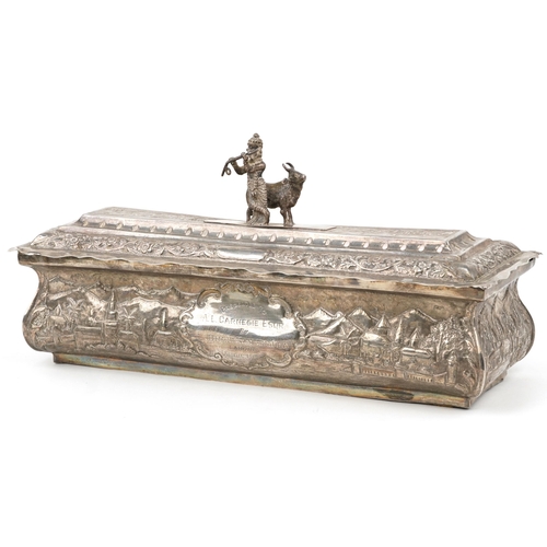 Anglo Indian unmarked silver presentation box, the casket profusely embossed with a continuous town scene, presented to A L Carnegie Esqr by L Dhani Ram on his retirement with related silk scrolls, the casket 18.5cm H x 37cm W x 13cm D, the casket 1110g