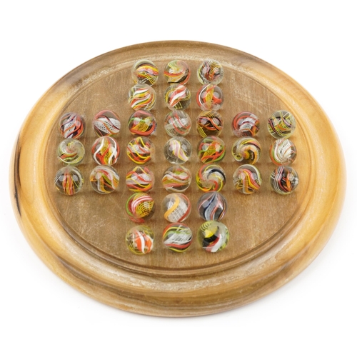 1504 - Boxed wooden solitaire board and selection of air twist marbles, the board 20cm in diameter