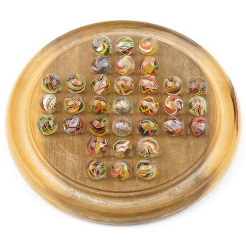 1504 - Boxed wooden solitaire board and selection of air twist marbles, the board 20cm in diameter