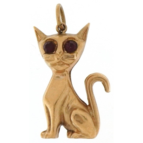 2068 - 9ct gold charm in the form of a seated cat with red glass eyes, 2.5cm high, 1.3g