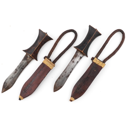 531 - Pair of African Tribal daggers with wooden handles housed in leather sheaths having rope twist strap... 