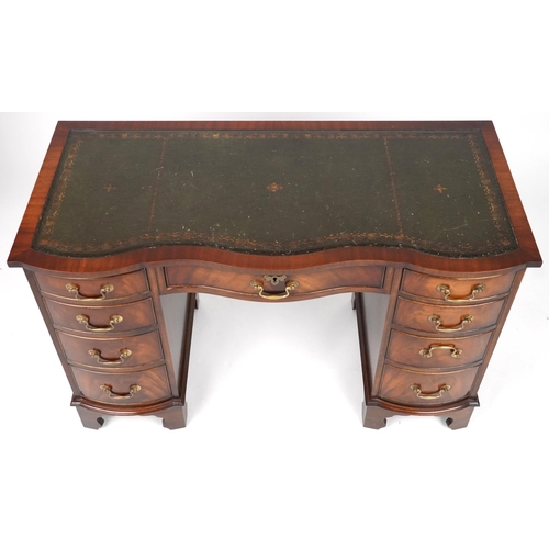 1012 - Mahogany serpentine front twin pedestal desk and a mahogany chair, the desk with nine drawers and gr... 