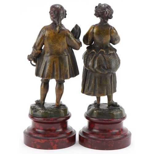 296 - Pair of cold painted spelter figures of a girl with dove reading a book and a gentleman topping his ... 