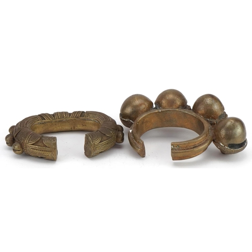 127 - Two tribal interest African brass cuff bangles, one with bells the largest 15cm in diameter