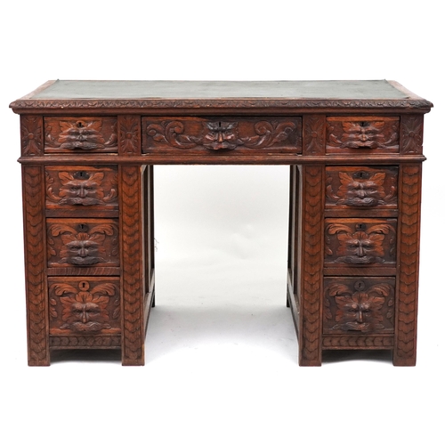 1003 - Victorian oak twin pedestal desk carved with a green man masks, fitted with an arrangement of nine d... 