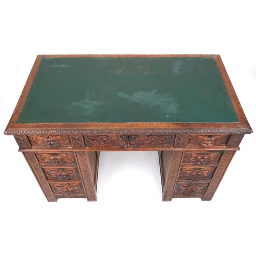 1003 - Victorian oak twin pedestal desk carved with a green man masks, fitted with an arrangement of nine d... 