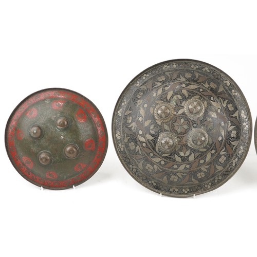 228 - Four Indo-Persian bronze Dhal shields decorated with flowers, the largest 38cm