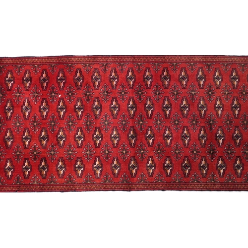 1031 - Rectangular carpet runner having an allover geometric design onto a red and blue ground, 330cm x 69c... 