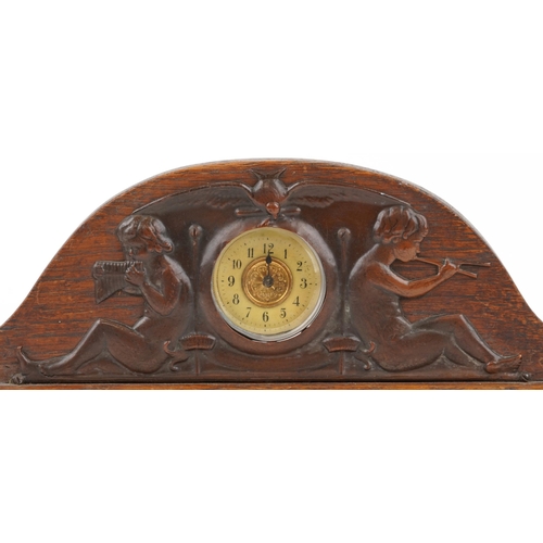 161 - Arts & Crafts oak and copper clock decorated with cherubs playing pan pipes, 32cm in diameter