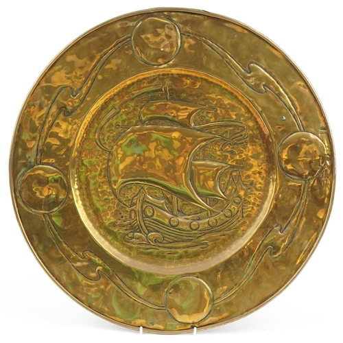 253 - Large Arts & Crafts brass charger decorated with a galleon in full sail, 52cm in diameter