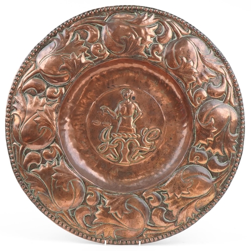 Large Arts & Crafts copper charger the central panel JMG and a man holding scales, 60cm in diameter