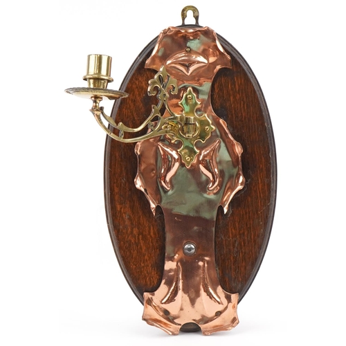 104 - Arts & Crafts Copper and brass wall sconce mounted on an oak plaque, 40cm high