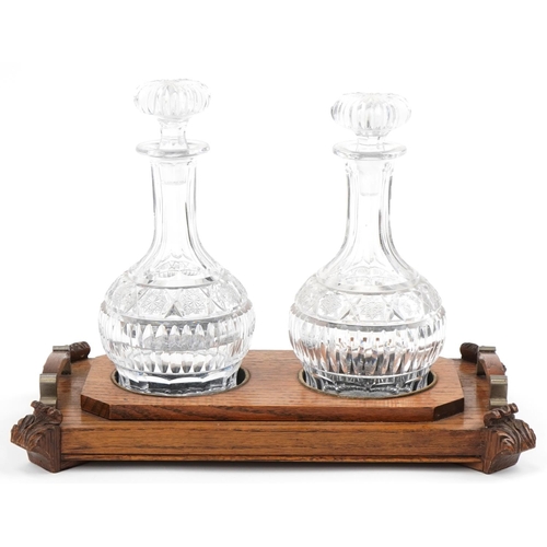 1164 - Victorian oak decanter stand with two good quality cut glass decanters, the stand 39cm in diameter