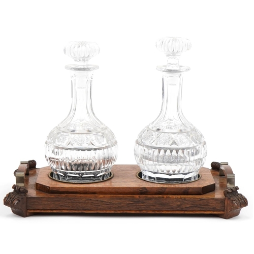 1164 - Victorian oak decanter stand with two good quality cut glass decanters, the stand 39cm in diameter