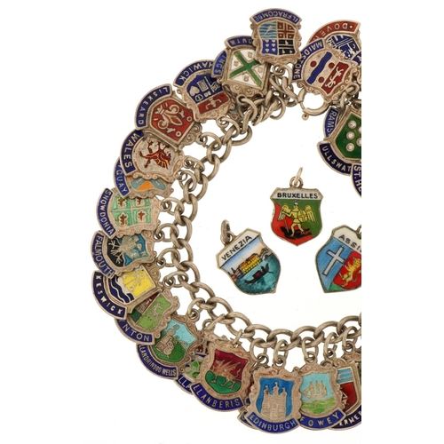 3435 - Silver charm bracelet with large collection of enamelled souvenir shield charms, 68.2g