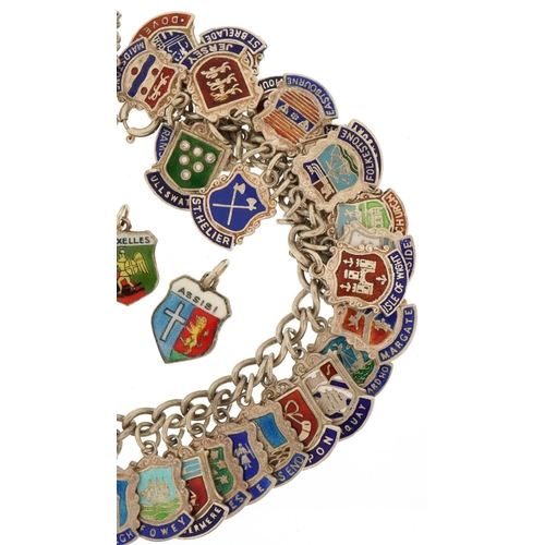 3435 - Silver charm bracelet with large collection of enamelled souvenir shield charms, 68.2g