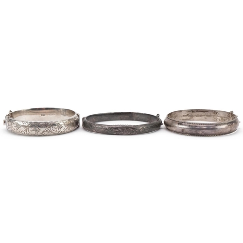 3177 - Three silver hinged bangles, two with engraved floral decoration, total 47.5g