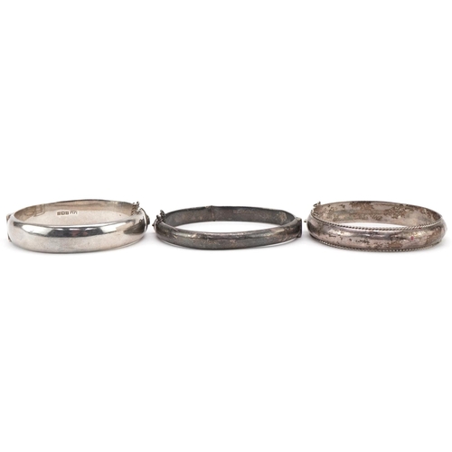 3177 - Three silver hinged bangles, two with engraved floral decoration, total 47.5g