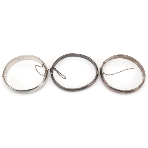 3177 - Three silver hinged bangles, two with engraved floral decoration, total 47.5g