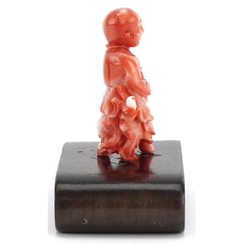 1211 - Chinese coral coloured okimono of a child on dog of Foo mounted on a wooden stand, 6cm in diameter