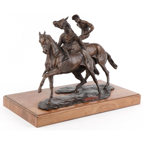 Large bronze figure group of two jockeys on horseback raised on a wooden plinth base, overall 57cm in length