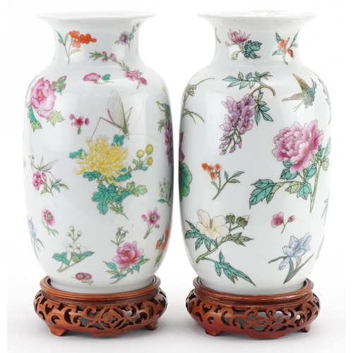 1016 - Pair of Chinese porcelain vases decorated with flowers and insects and mounted on wooden stands, eac... 