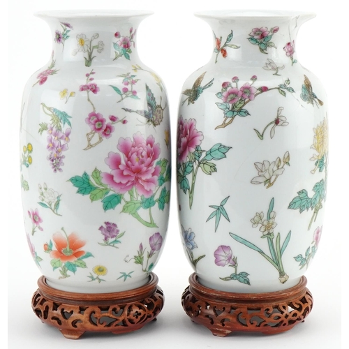 1016 - Pair of Chinese porcelain vases decorated with flowers and insects and mounted on wooden stands, eac... 