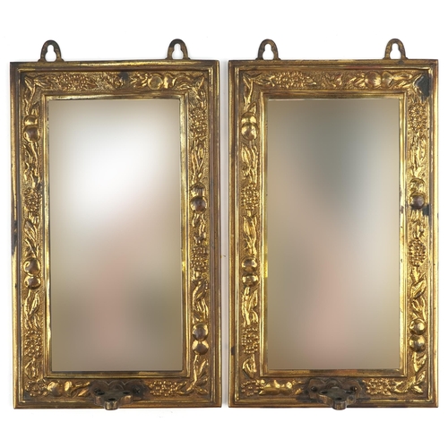 150 - Pair of Arts & Crafts brass wall mirrors decorated with fruit, each 38cm x 23cm