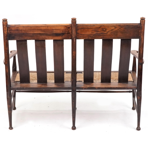 532 - Early 20th century Arts & Crafts oak two seat bench, probably by William Birch, the carved splat bac... 