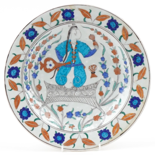 1283 - Turkish Ottoman Iznik plate hand painted with a figure and stylized flowers, 32cm in diameter