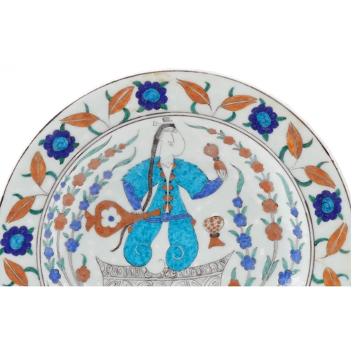 1283 - Turkish Ottoman Iznik plate hand painted with a figure and stylized flowers, 32cm in diameter