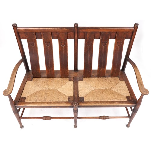 531 - Early 20th century Arts & Crafts oak two seat bench, probably by William Birch, the carved splat bac... 