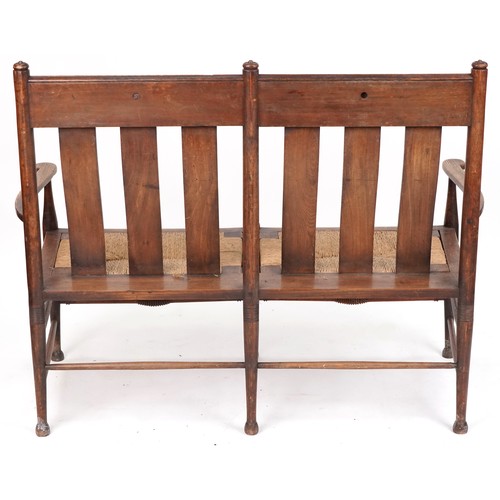 531 - Early 20th century Arts & Crafts oak two seat bench, probably by William Birch, the carved splat bac... 