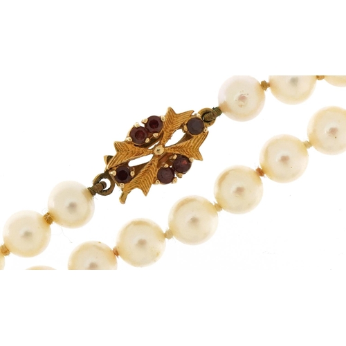 3335 - Cultured pearl necklace with 9ct gold garnet clasp, 44cm in length, 23.6g