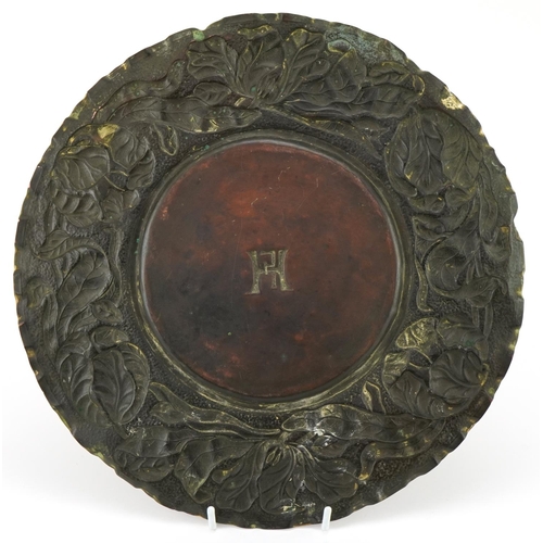 107 - Arts & Crafts copper plate with stylized floral border, initial HF to the centre, 30cm in diameter