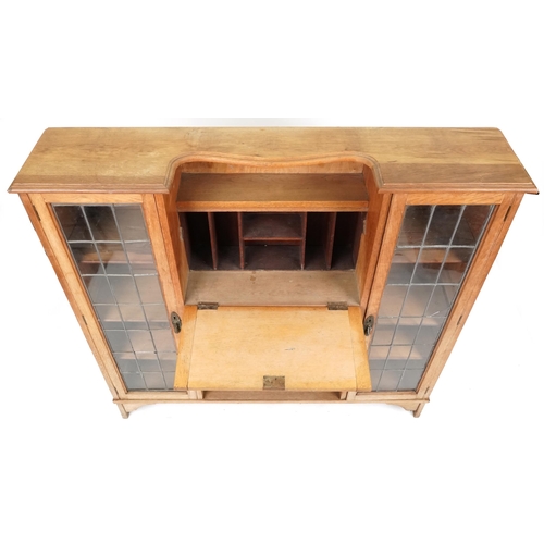 598 - Early 20th century Arts & Crafts style oak bureau bookcase fitted with a pair of leaded glazed doors... 