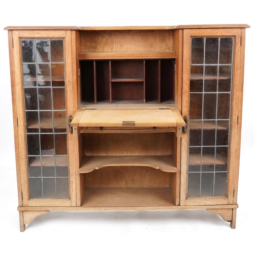 598 - Early 20th century Arts & Crafts style oak bureau bookcase fitted with a pair of leaded glazed doors... 