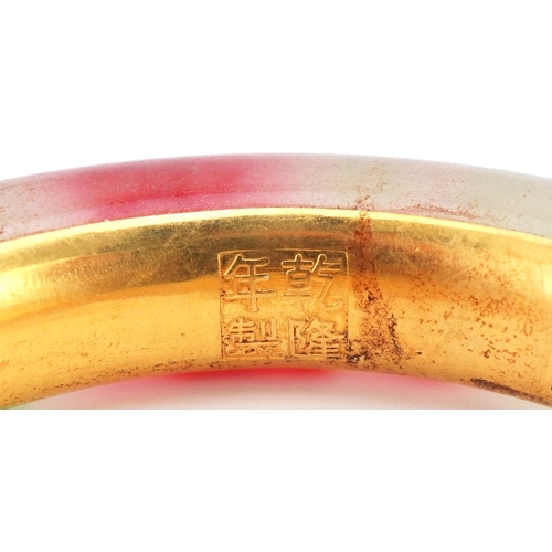 3427 - Chinese multi coloured jade and gilt metal bangle, impressed marks to the interior, 9cm in diameter,... 