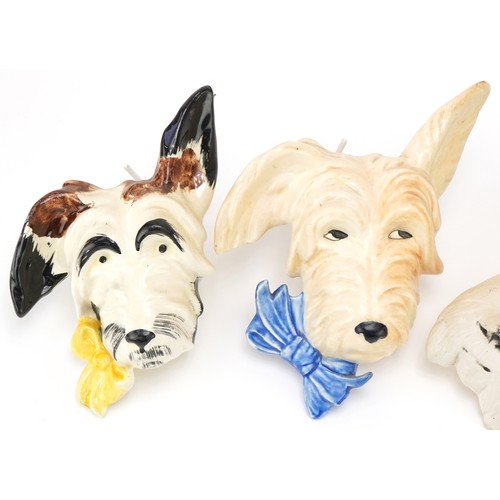 427 - Four terrier dog wall plaques including a plaster example, the tallest 17cms high