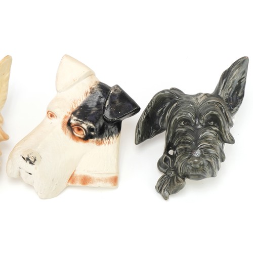 427 - Four terrier dog wall plaques including a plaster example, the tallest 17cms high