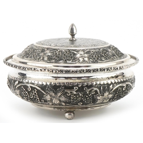  Middle Eastern silver bowl and cover raised on three ball feet profusely embossed with fruit on vine... 