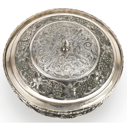  Middle Eastern silver bowl and cover raised on three ball feet profusely embossed with fruit on vine... 