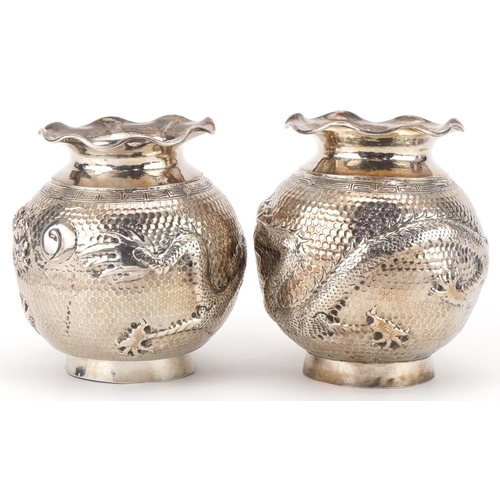 149 - Pair of Chinese export silver globular vases embossed with a dragon chasing a pearl, indistinct mark... 