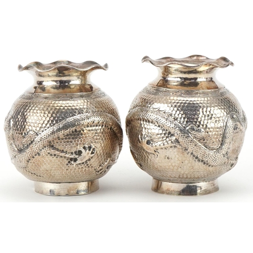 149 - Pair of Chinese export silver globular vases embossed with a dragon chasing a pearl, indistinct mark... 