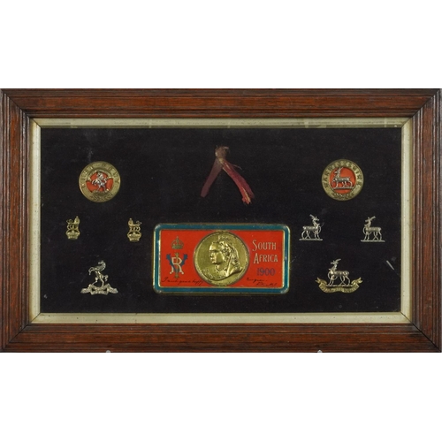 2626 - Military interest cap badges and South Africa 1900 tin lid housed in a glazed frame - West Kent and ... 